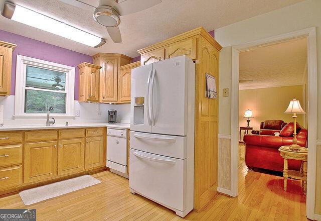 kitchen featuring ceiling fan, light brown cabinets, light wood-type flooring, and white appliances