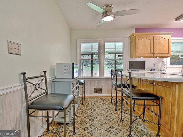 kitchen featuring ceiling fan, wooden walls, and light brown cabinets