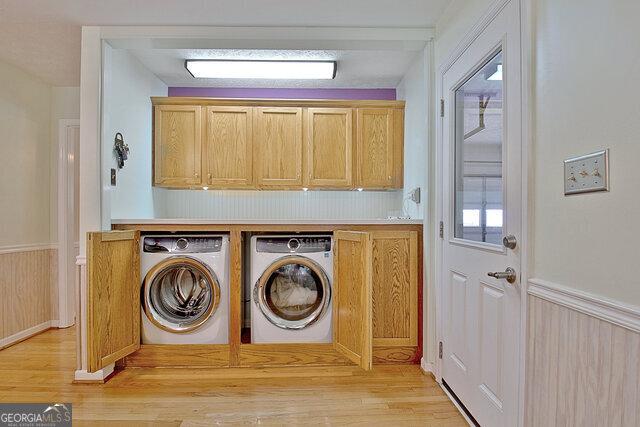 washroom featuring cabinets, light hardwood / wood-style flooring, and washing machine and clothes dryer