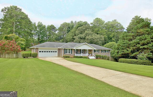 ranch-style house with a front lawn, covered porch, and a garage