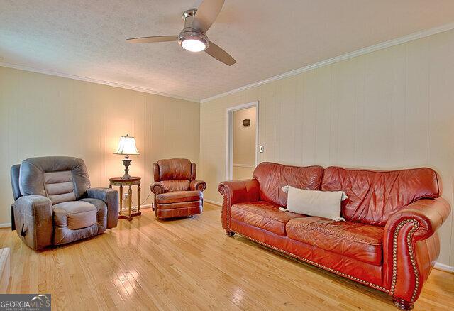 living room with hardwood / wood-style floors, a textured ceiling, ceiling fan, and crown molding