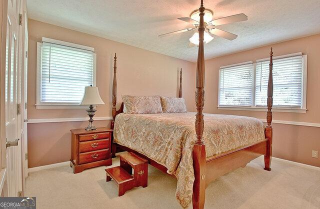 carpeted bedroom featuring ceiling fan and a textured ceiling