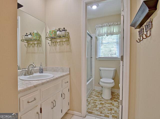 full bathroom with vanity, enclosed tub / shower combo, and toilet