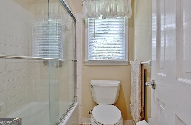 bathroom featuring shower / bath combination with glass door and toilet