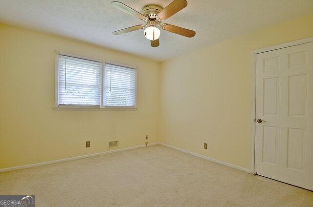 unfurnished room featuring ceiling fan and light carpet