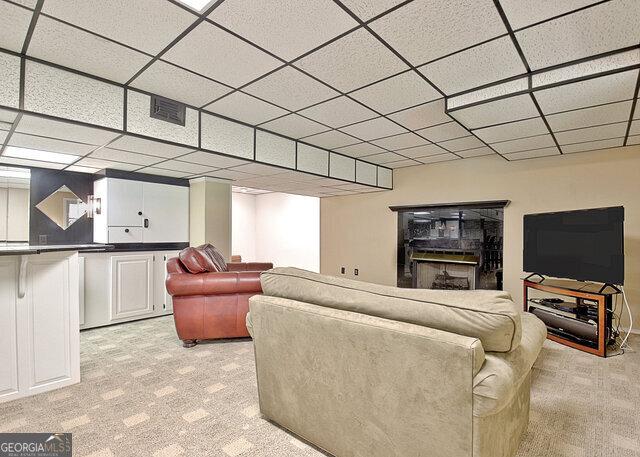 living room featuring a paneled ceiling and light carpet