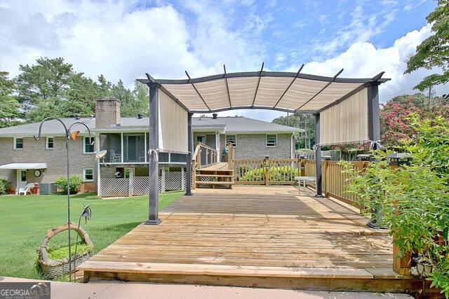 back of property with a lawn, a pergola, a deck, and a sunroom