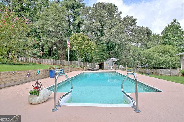 view of swimming pool featuring a patio and a storage unit