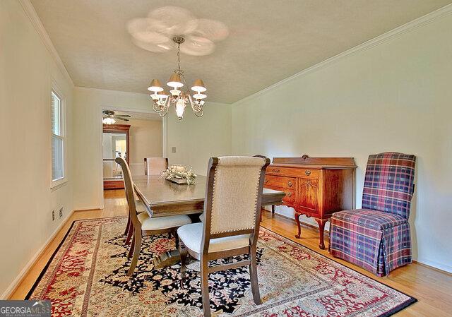 dining area featuring a notable chandelier, crown molding, and light hardwood / wood-style flooring