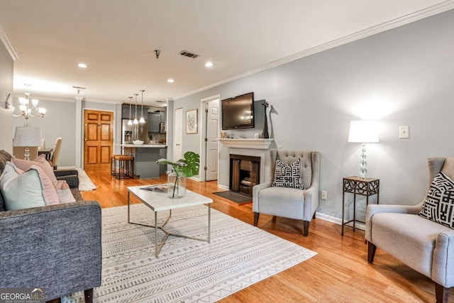 living room with light wood-type flooring, an inviting chandelier, and ornamental molding