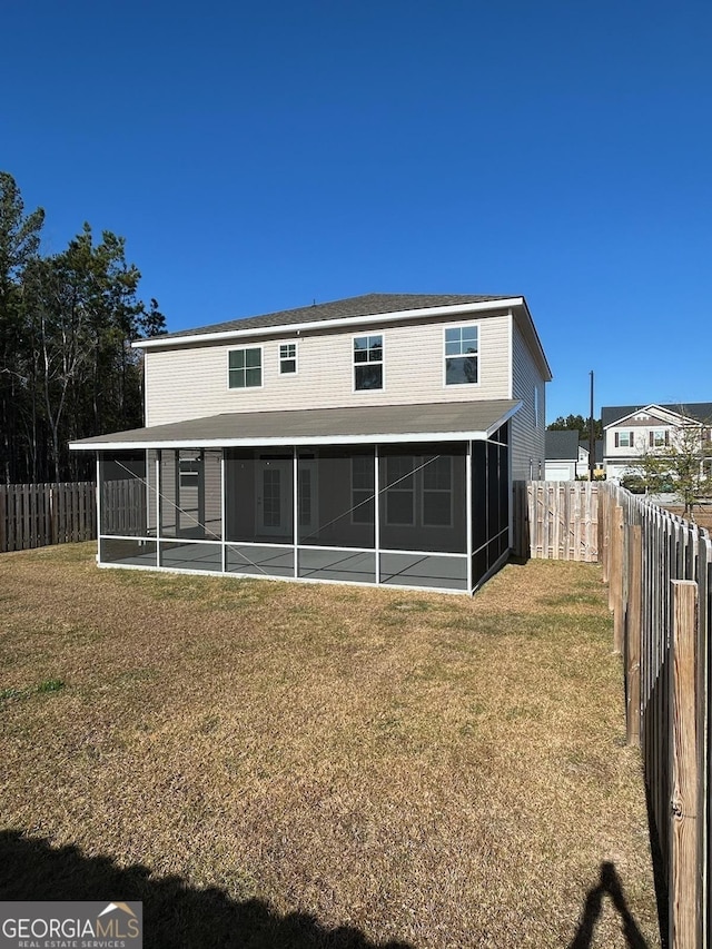 rear view of house featuring a lawn and a sunroom