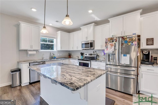 kitchen featuring appliances with stainless steel finishes, sink, a center island, white cabinetry, and hanging light fixtures