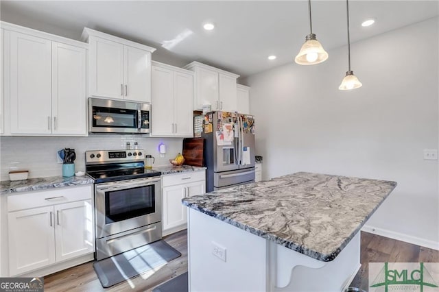 kitchen with decorative backsplash, appliances with stainless steel finishes, a kitchen bar, decorative light fixtures, and white cabinetry