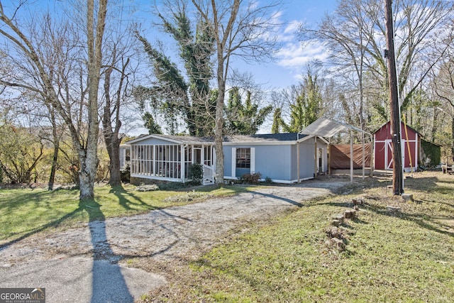 view of front of property with a sunroom, a shed, and a front yard