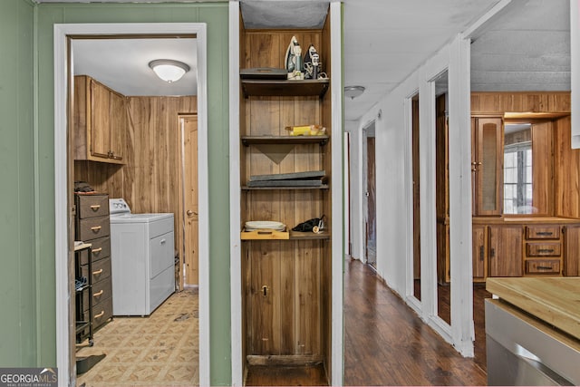 laundry room featuring separate washer and dryer, wood walls, and cabinets