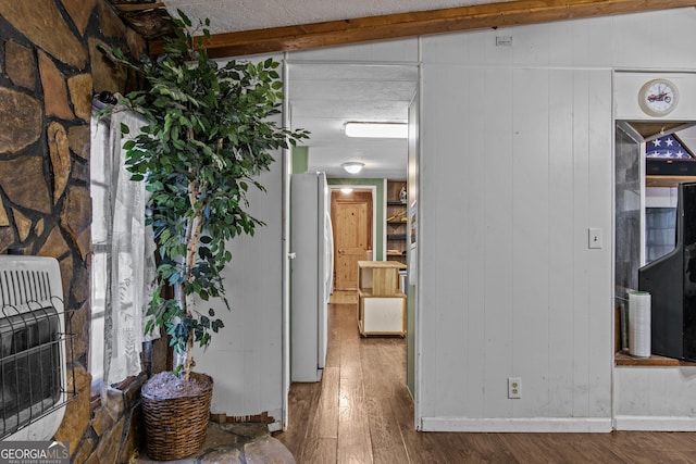 hall featuring hardwood / wood-style floors, lofted ceiling with beams, wooden walls, and heating unit