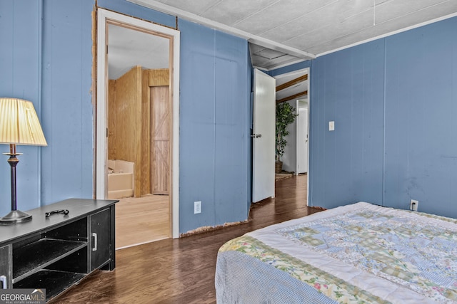 bedroom featuring dark hardwood / wood-style floors, ensuite bath, and wood walls