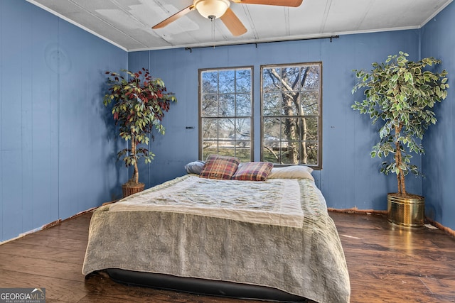 bedroom featuring ceiling fan, wood walls, ornamental molding, and dark wood-type flooring