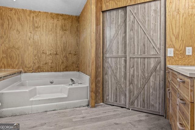 bathroom featuring a washtub, wood-type flooring, vanity, and wood walls