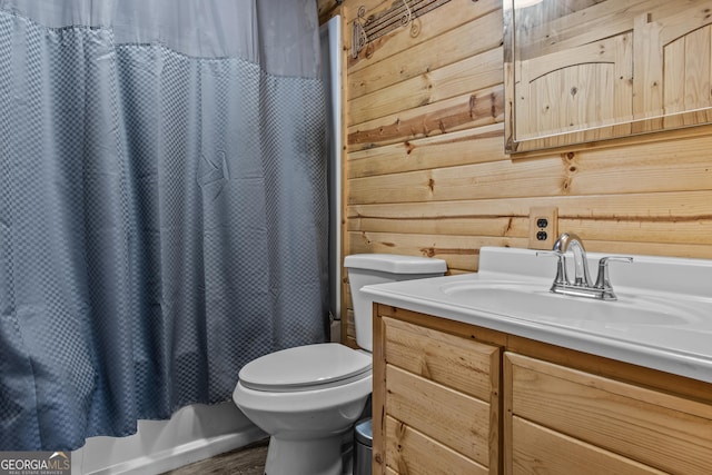 bathroom featuring wood walls, toilet, vanity, and walk in shower