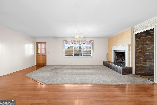 unfurnished living room with a tile fireplace, wood-type flooring, a chandelier, and ornamental molding