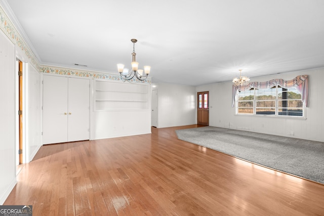 unfurnished dining area with hardwood / wood-style floors, crown molding, and a chandelier