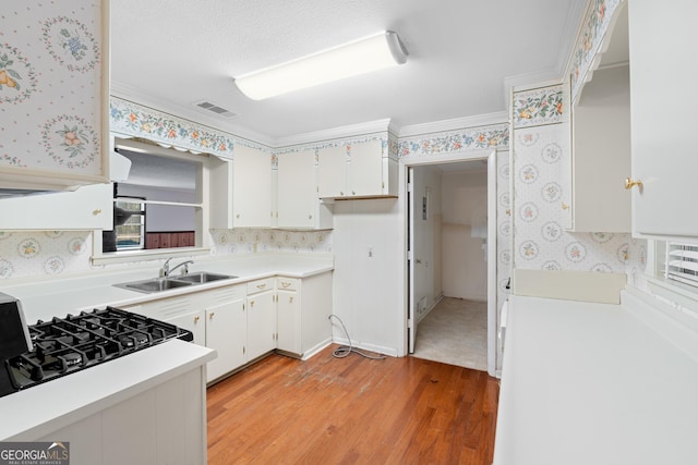 kitchen with light wood-type flooring, ornamental molding, sink, range, and white cabinetry