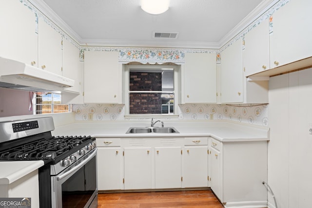 kitchen with stainless steel gas stove, crown molding, white cabinetry, and sink