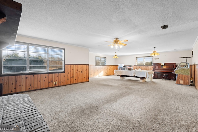 bedroom featuring carpet, wood walls, a textured ceiling, and multiple windows