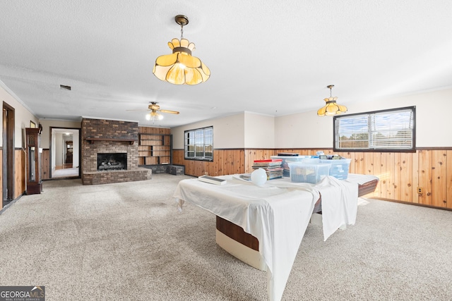 rec room with ceiling fan, a brick fireplace, crown molding, a textured ceiling, and carpet