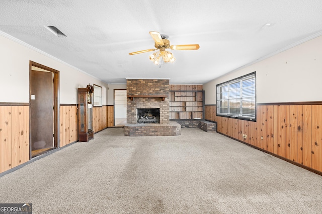 unfurnished living room featuring a fireplace, carpet floors, ceiling fan, and ornamental molding