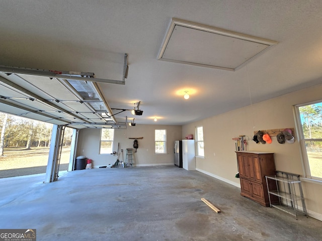 garage with stainless steel fridge, white refrigerator, and a garage door opener