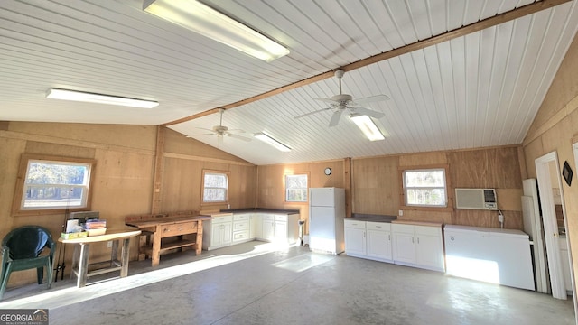 kitchen featuring a wealth of natural light, wooden walls, lofted ceiling, and white refrigerator