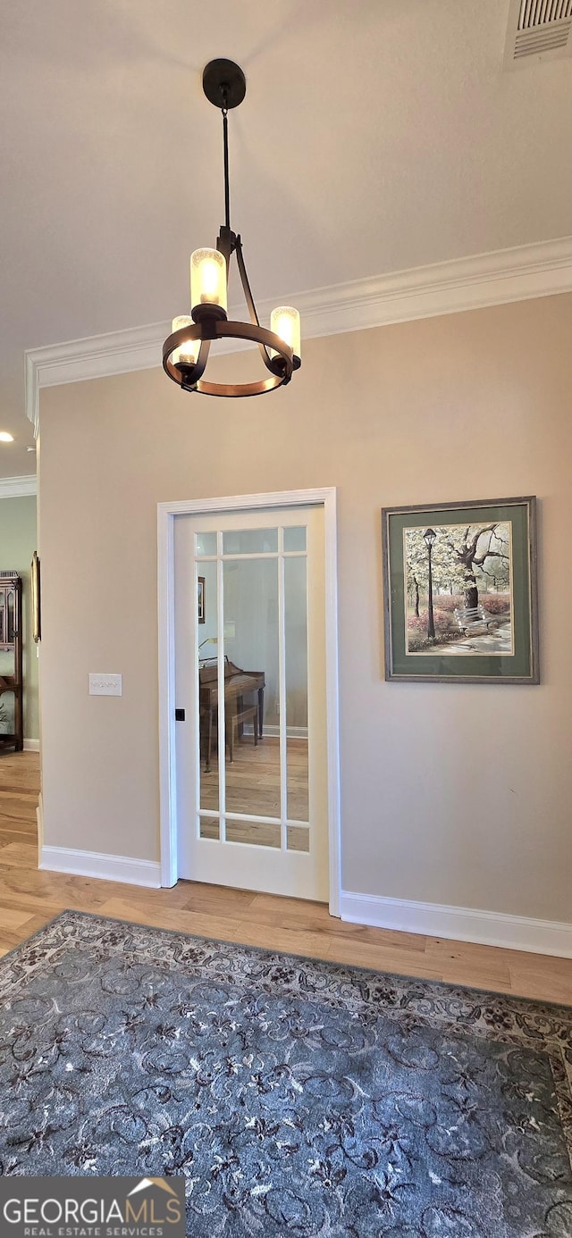 interior space with crown molding, hardwood / wood-style floors, and an inviting chandelier