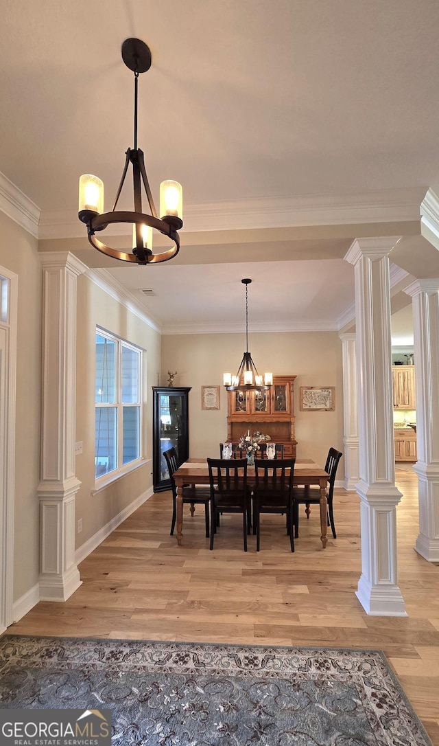 dining area with light wood-type flooring, crown molding, and a notable chandelier