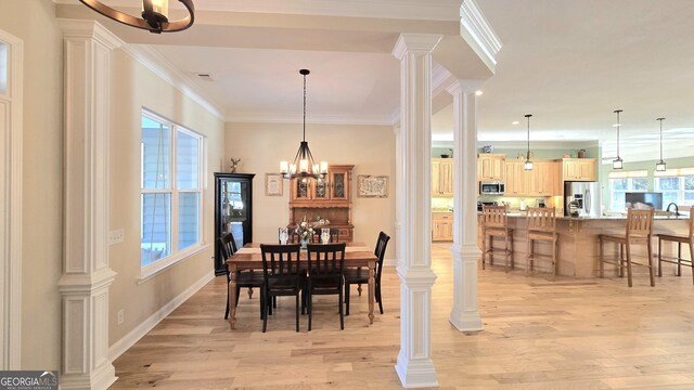 dining space featuring sink, ornamental molding, light hardwood / wood-style flooring, and a chandelier