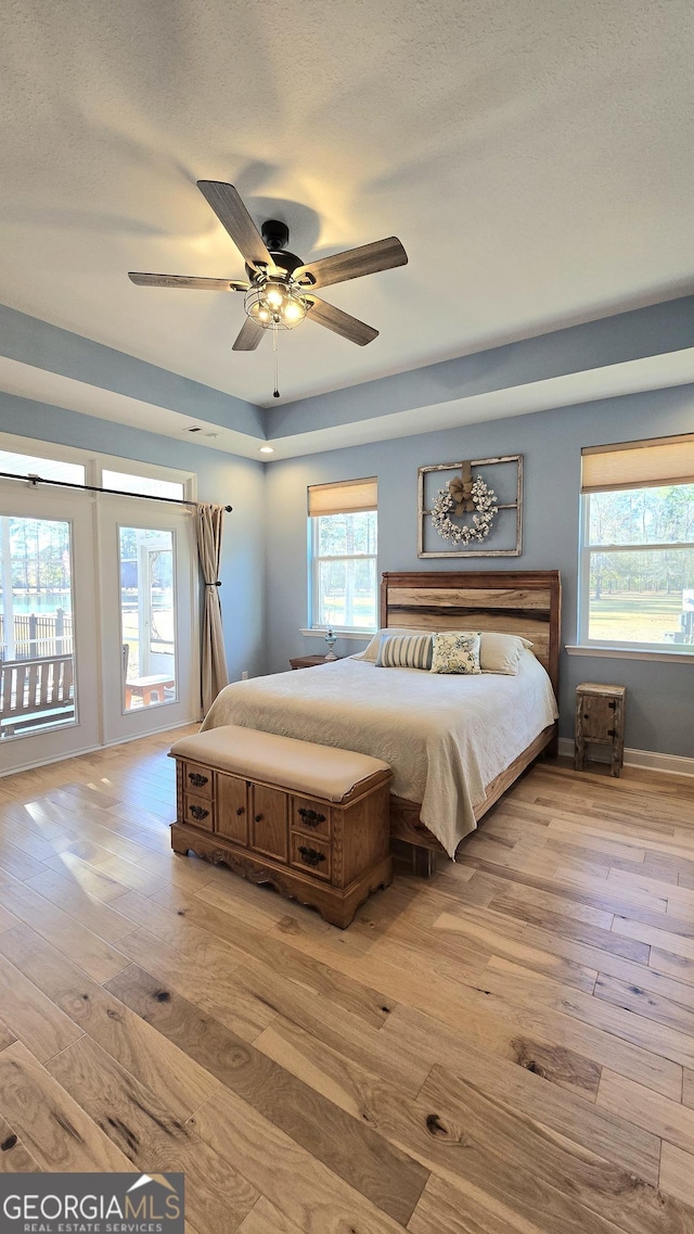 unfurnished bedroom featuring ceiling fan, light hardwood / wood-style floors, and a tray ceiling