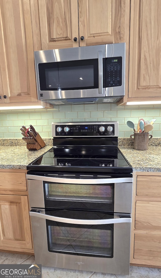 kitchen with light stone countertops, appliances with stainless steel finishes, and tasteful backsplash