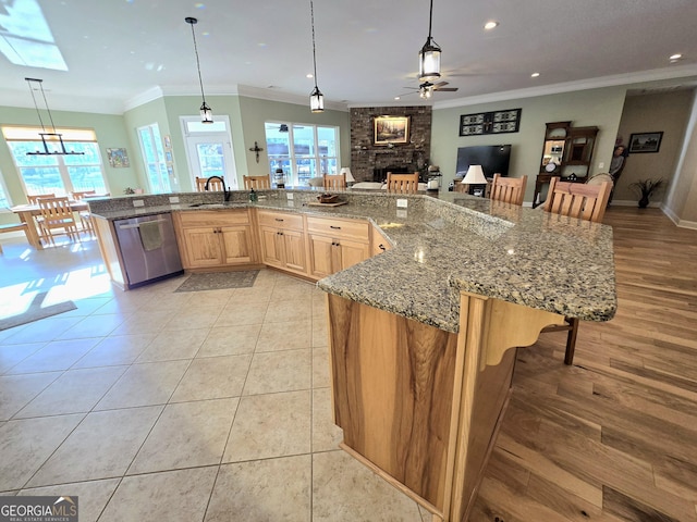 kitchen with a skylight, ceiling fan, dishwasher, light brown cabinets, and decorative light fixtures