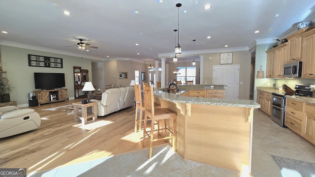 kitchen with appliances with stainless steel finishes, light brown cabinets, hanging light fixtures, and ceiling fan