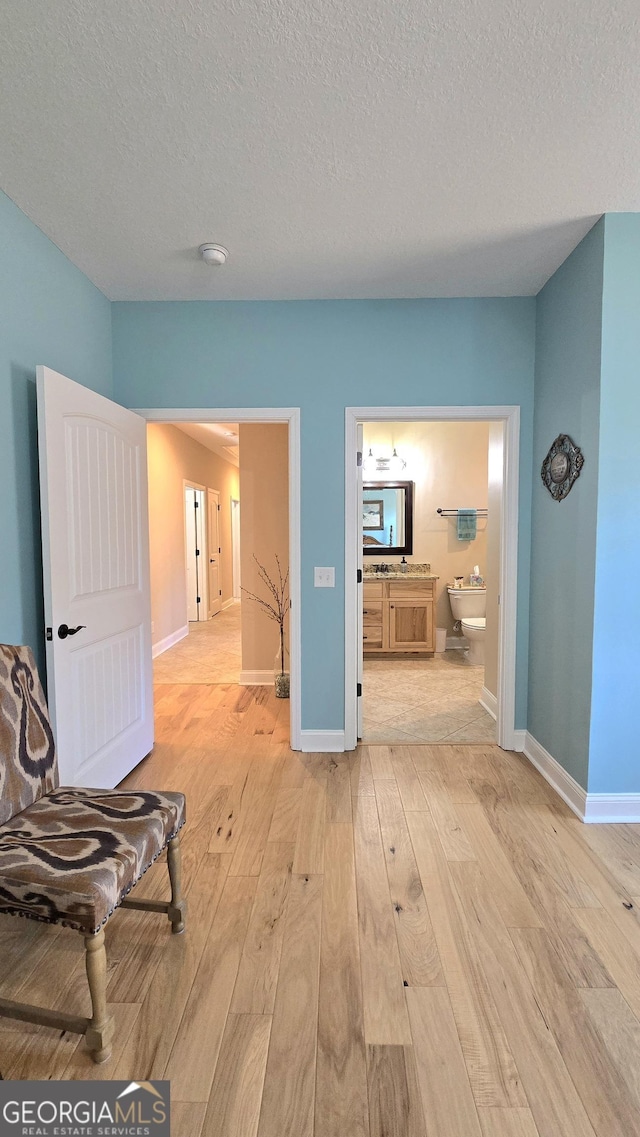 corridor with light hardwood / wood-style floors and a textured ceiling