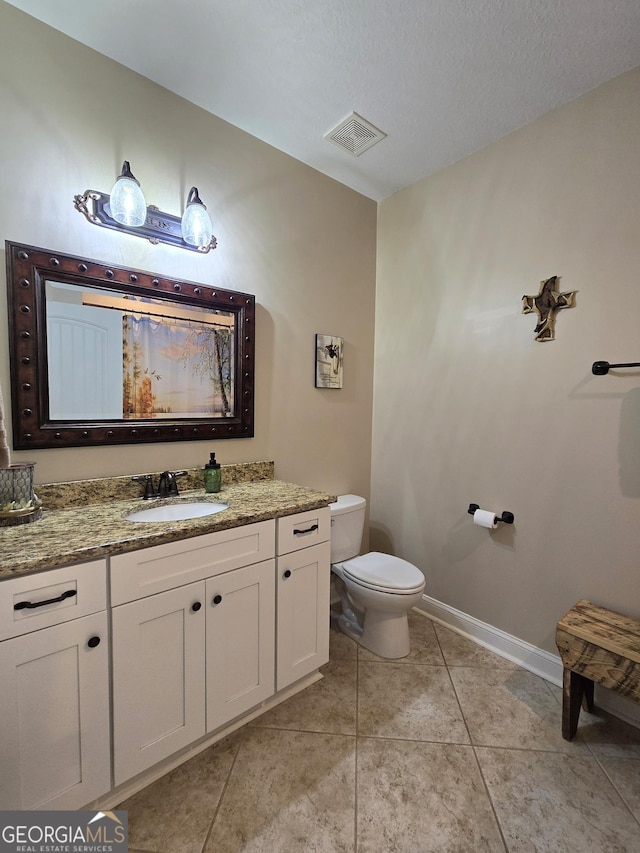 bathroom featuring tile patterned flooring, a textured ceiling, vanity, and toilet