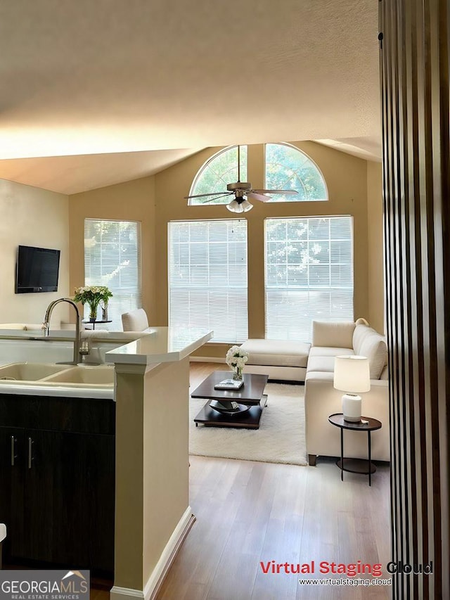 living room with vaulted ceiling, wood-type flooring, sink, and ceiling fan