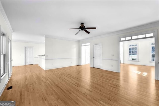 unfurnished living room featuring ceiling fan, a healthy amount of sunlight, light wood-type flooring, and ornamental molding