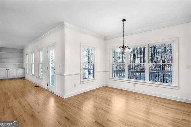 unfurnished dining area featuring hardwood / wood-style floors, built in features, ornamental molding, and a chandelier