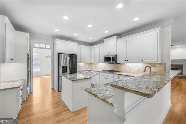 kitchen featuring white cabinets, a kitchen island, kitchen peninsula, and stainless steel appliances