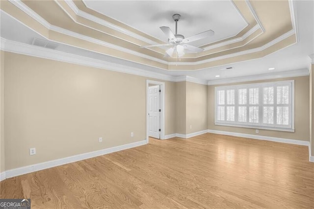 spare room featuring ceiling fan, ornamental molding, light hardwood / wood-style flooring, and a tray ceiling