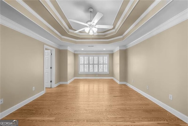 spare room with ceiling fan, light hardwood / wood-style floors, crown molding, and a tray ceiling