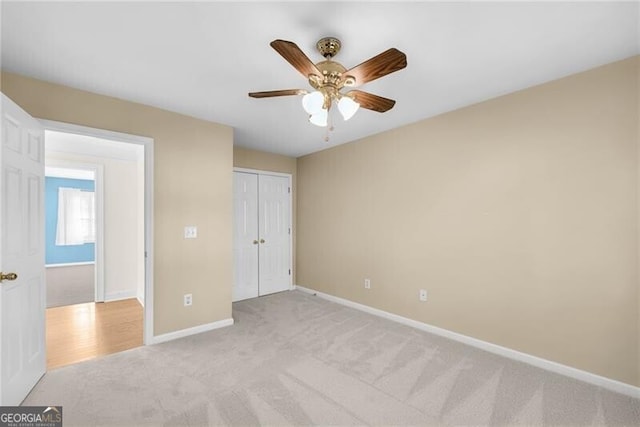 unfurnished bedroom with ceiling fan, a closet, and light carpet