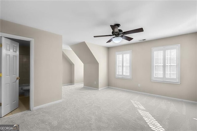 bonus room with ceiling fan and light colored carpet